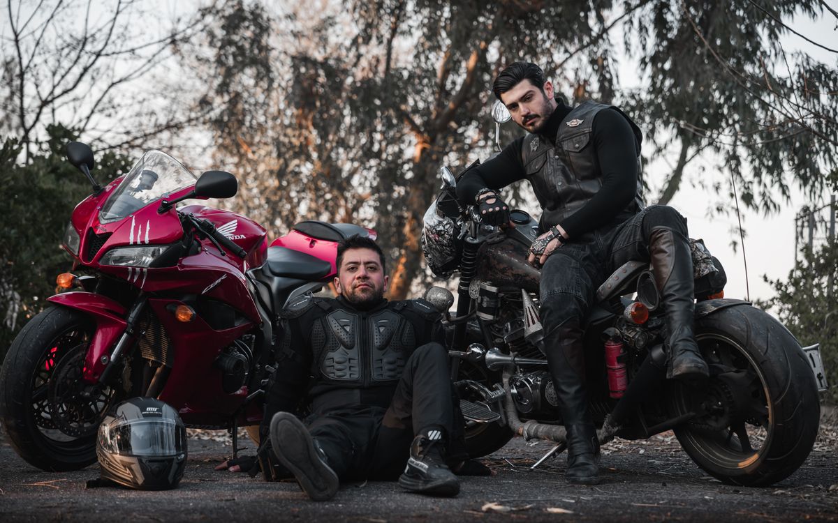 Moteros con equipo de cuero junto a una motocicleta clásica