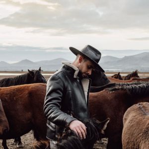 Una figura con recio cuero western ante un paisaje abierto