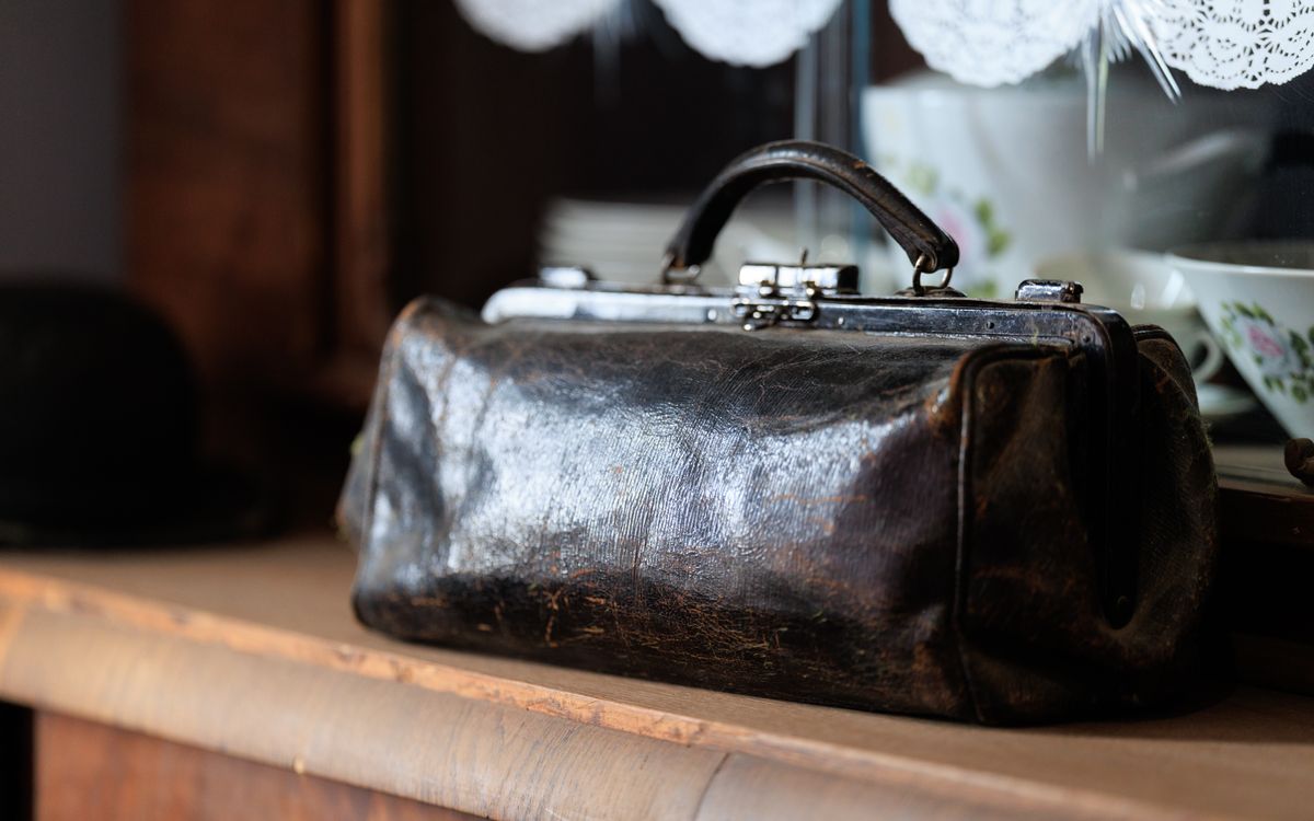 Un bolso de cuero vintage sobre un estante de madera, rico en pátina