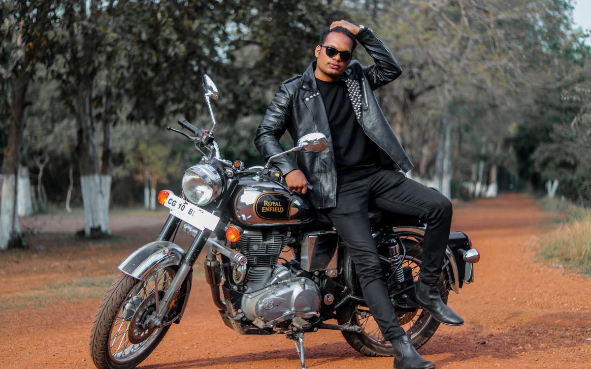 Buneri.es | Bomber, motera o café racer: ¿qué estilo de chaqueta de cuero te queda mejor? Joven posando junto a una moto en un camino de tierra, luciendo una chaqueta de cuero ajustada