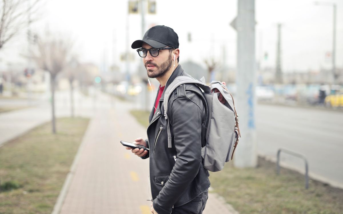 Buneri.es | Chaqueta de Cuero Sobre una Sudadera con Capucha: Cómo Lograr que el Streetwear Funcione Joven con estilo en Budapest revisando su móvil en una calle concurrida