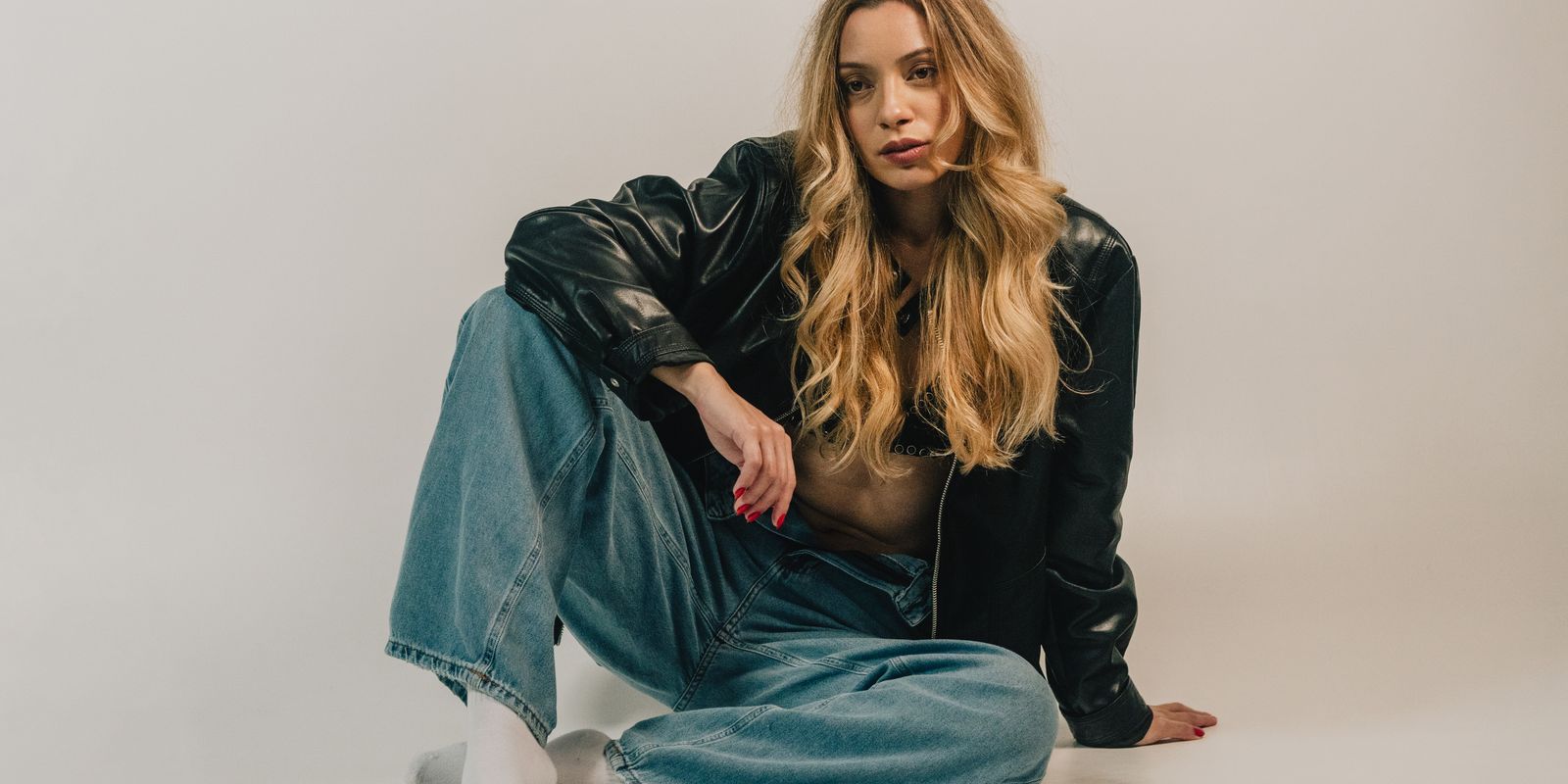 Buneri.es | Chaqueta de Cuero o Chaqueta Vaquera: ¿Cuál Elegir? Fashion-forward woman sitting casually in denim and leather jacket