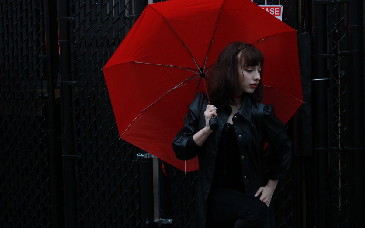 Buneri.es | ¿Se puede llevar una chaqueta de cuero bajo la lluvia? Mujer caucásica con chaqueta de cuero negra y paraguas rojo al aire libre