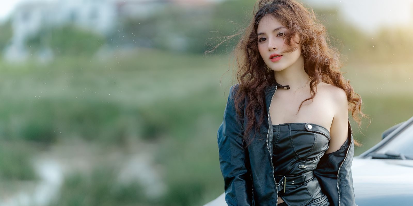 Buneri.es | Cómo Combinar una Chaqueta de Piel con un Vestido Mujer joven con chaqueta de piel posando con seguridad al aire libre junto a un coche