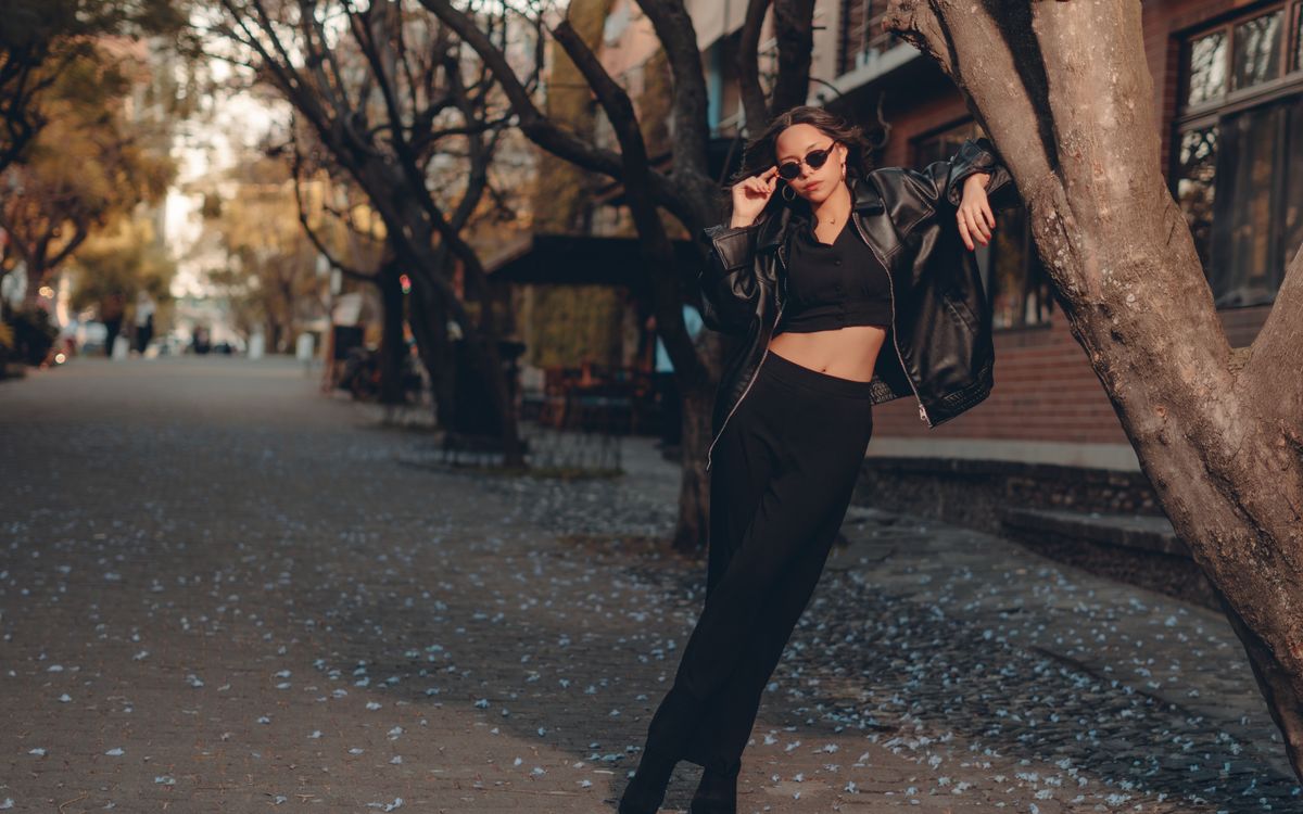 Buneri.es | Cómo Combinar una Chaqueta de Piel con un Vestido Mujer elegante con look negro posando en una escena urbana otoñal con hojas caídas
