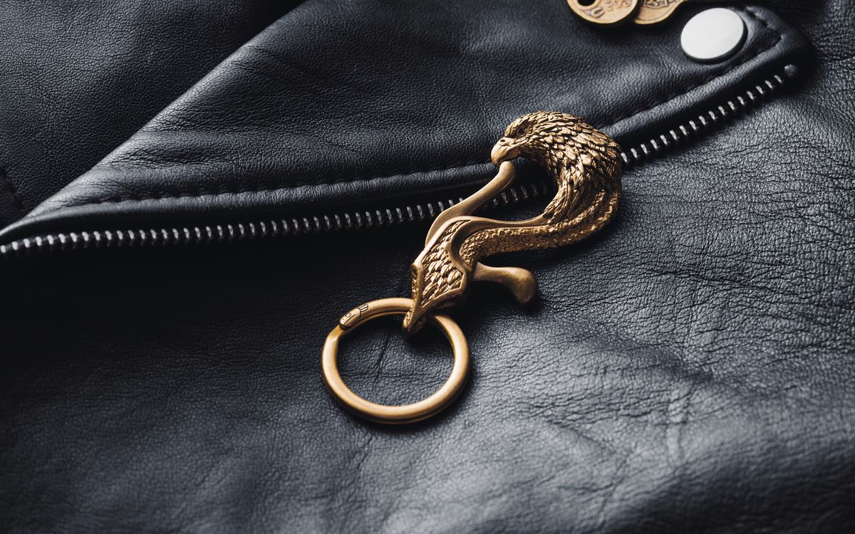 Buneri.es | Cómo Reconocer una Chaqueta de Cuero de Calidad Antes de Comprar Primer plano de un detalle de latón sobre una chaqueta de cuero con textura