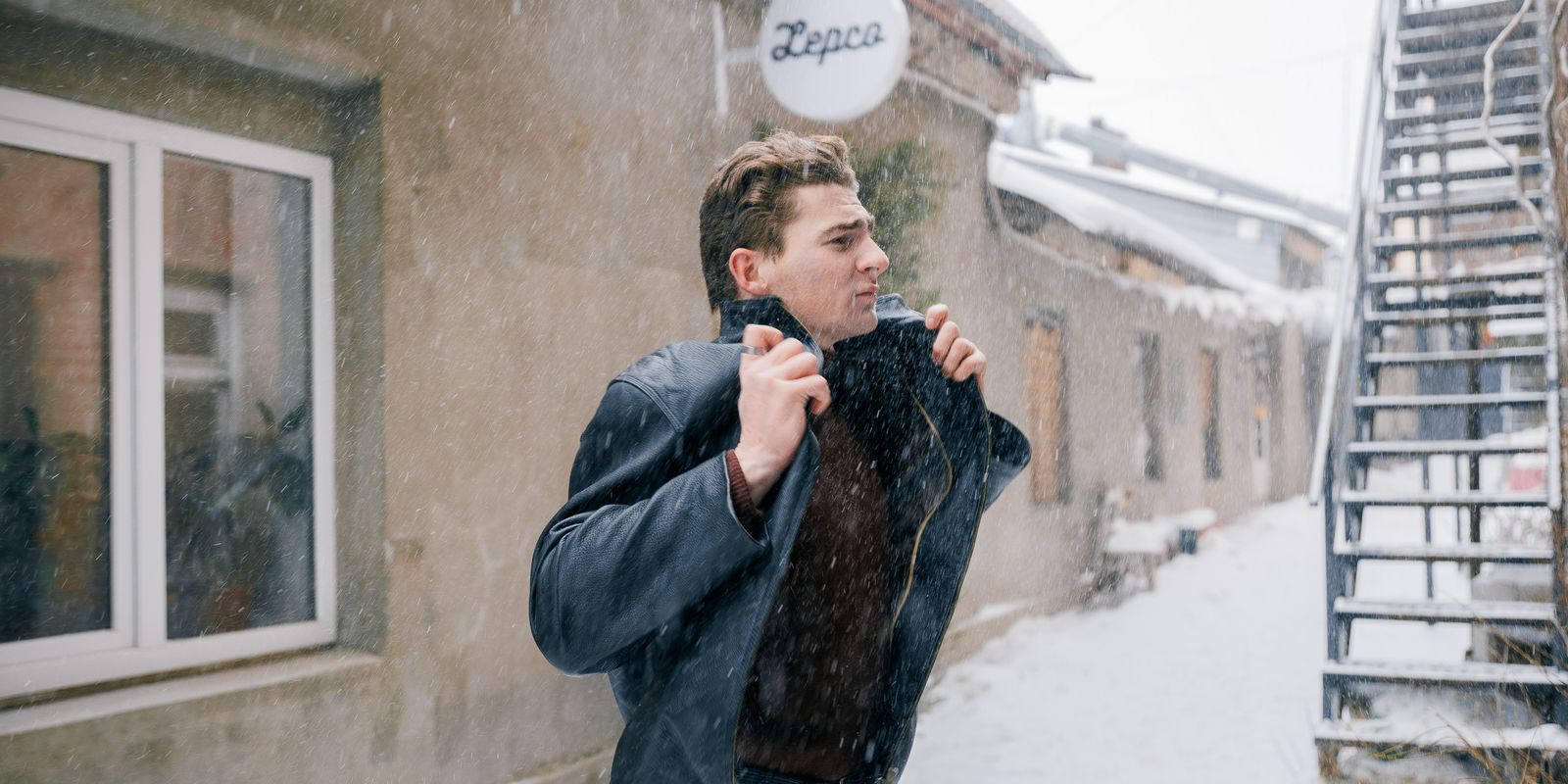 Buneri.es | Estilos de Cuello de Chaqueta de Cuero Explicados: Alto, Mao, con Solapa o Sin Él Hombre caminando al aire libre en invierno subiéndose el cuello contra el frío