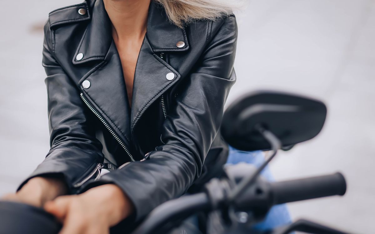 Buneri.es | Estilos de Cuello de Chaqueta de Cuero Explicados: Alto, Mao, con Solapa o Sin Él Primer plano de una mujer con chaqueta de cuero negra de cuello alto montando en moto