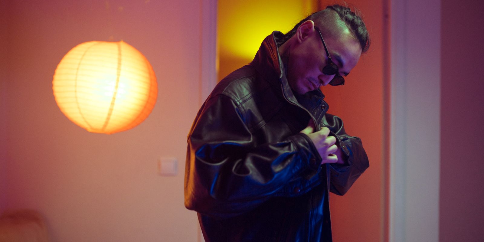 Buneri.es | ¿Las chaquetas de piel se estiran o encogen? La guía del amoldado Hombre elegante con chaqueta de piel negra ajustándose el cuello en un ambiente interior cálido