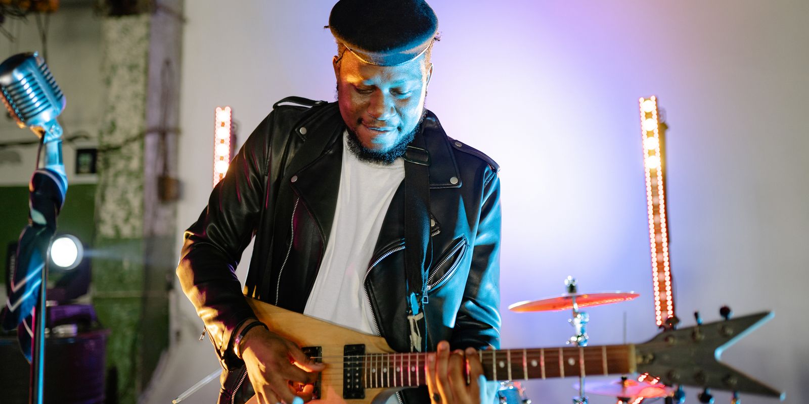 Buneri.es | Por qué los directores tecnológicos y las estrellas del rock viven en chaqueta de cuero Guitarrista tocando una guitarra eléctrica en el escenario con luces vibrantes, vistiendo chaqueta de cuero y gorra plana