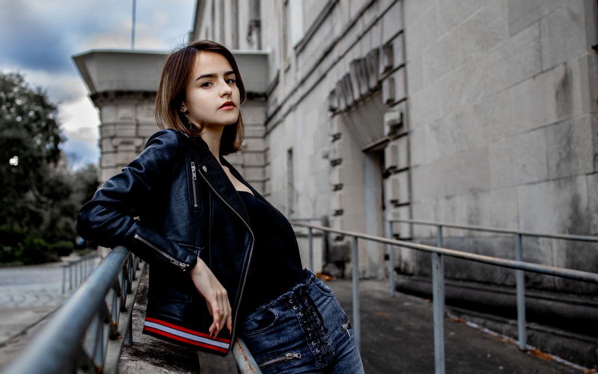 Joven con estilo posando con confianza en chaqueta de cuero sobre un fondo urbano