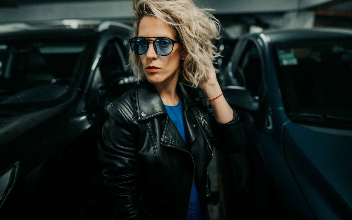 Buneri.es | ¿Qué ponerse debajo de una chaqueta de cuero? (Hombre y mujer) Mujer elegante con chaqueta de cuero, posando con confianza en un entorno urbano