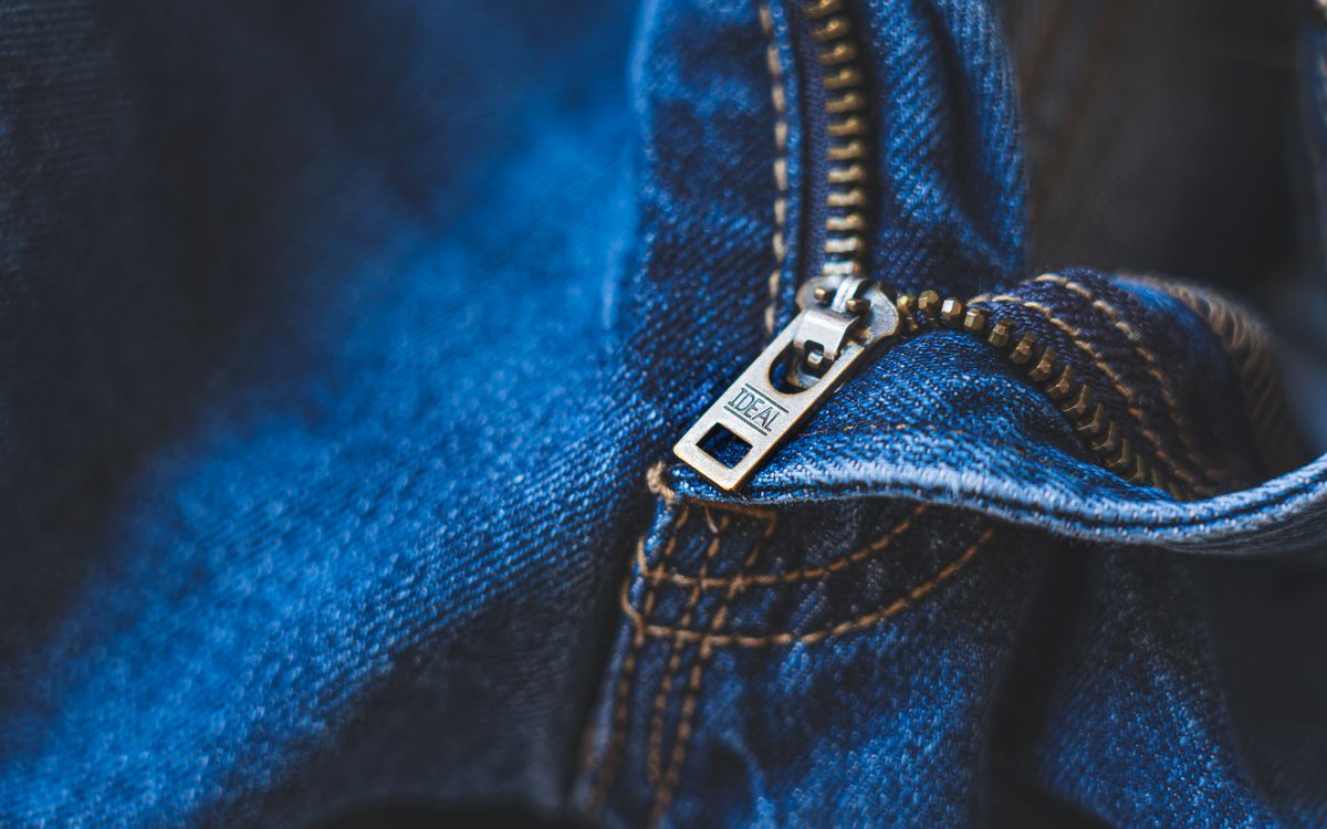 Buneri.es | Reparar una chaqueta de cuero: rotos, arañazos y cremallera Close-up of blue denim fabric featuring a metal zipper with detailed stitching